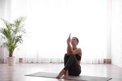 Photo of Young woman practicing eagle asana in yoga studio. Garudasana pose