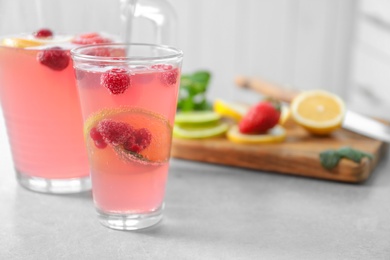 Jug and glass of fresh lemonade with berries on table