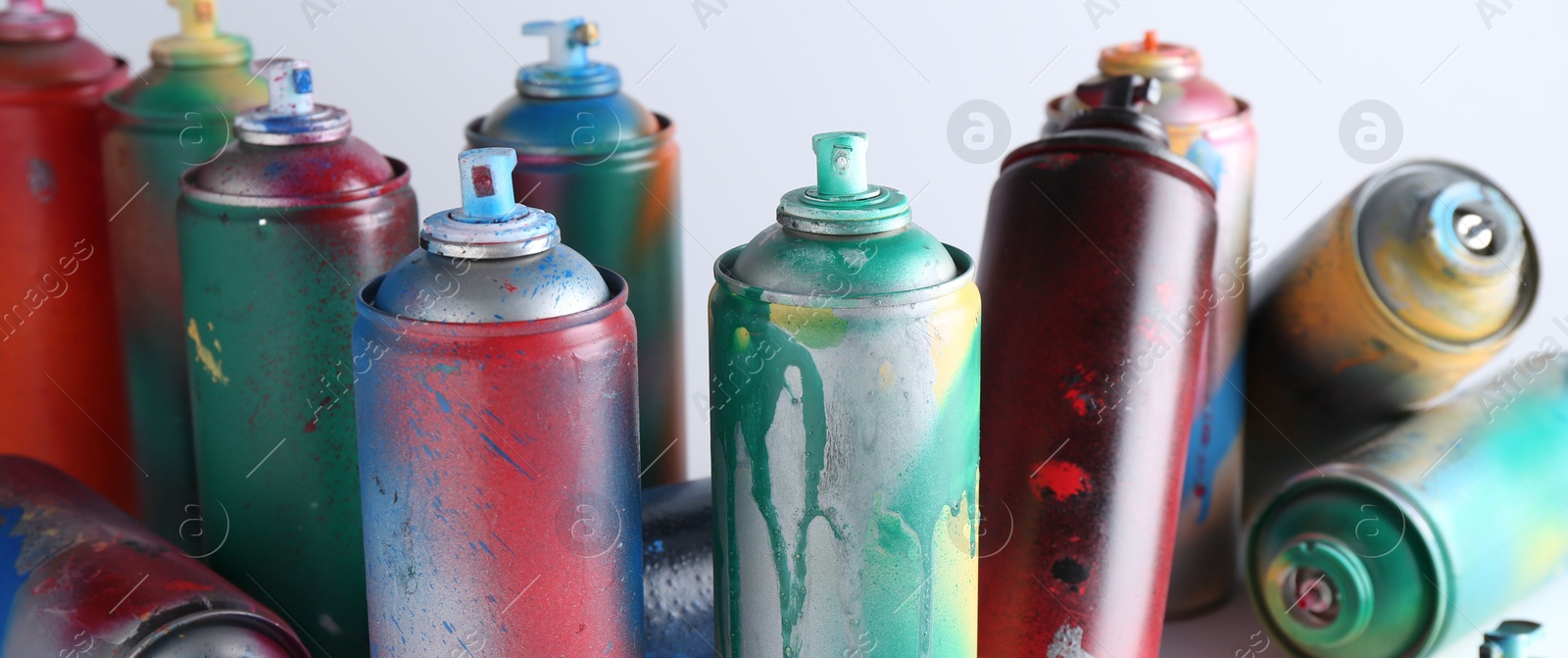 Photo of Many spray paint cans on white background, closeup