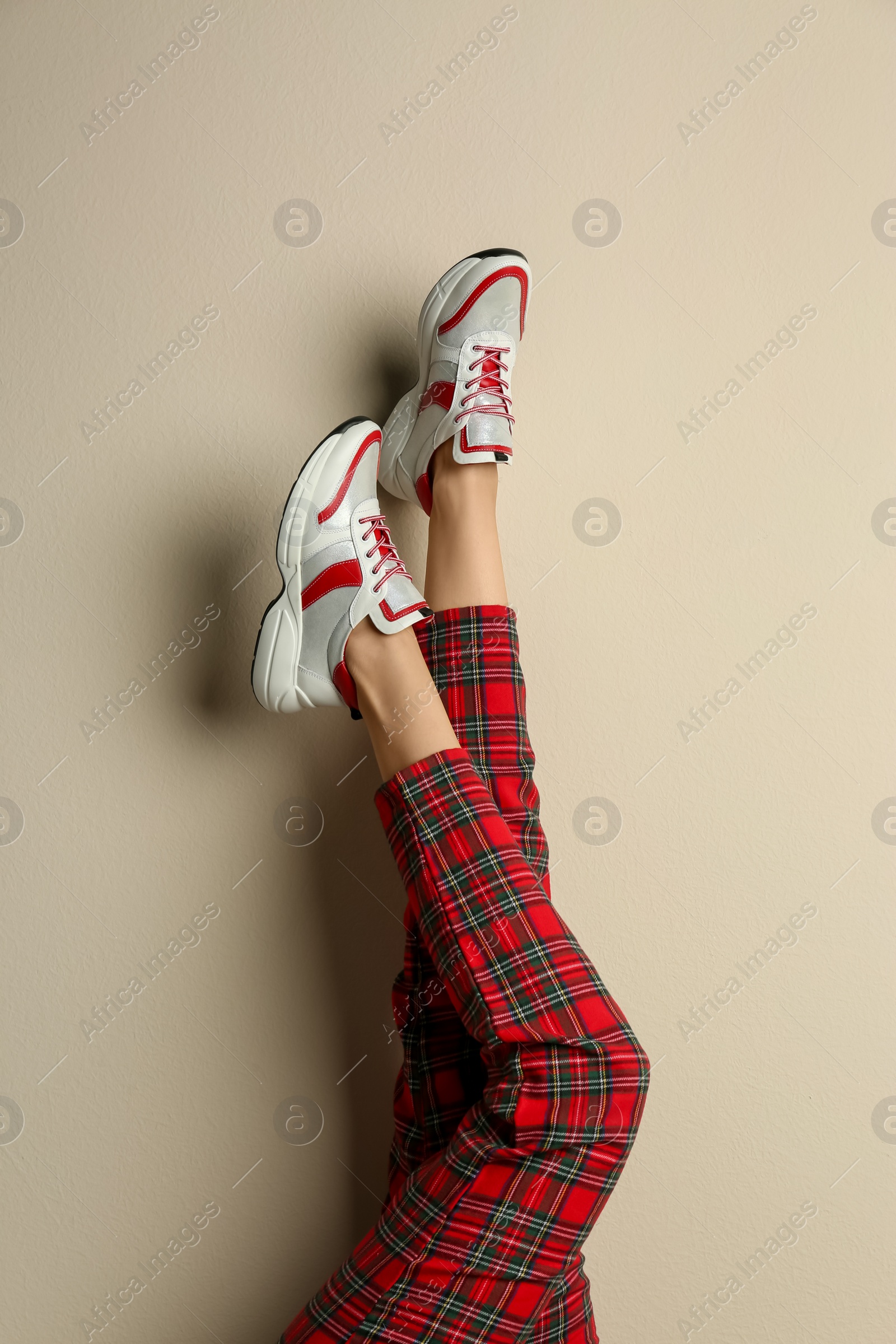 Photo of Woman wearing sneakers on beige background, closeup