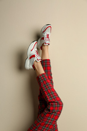 Woman wearing sneakers on beige background, closeup