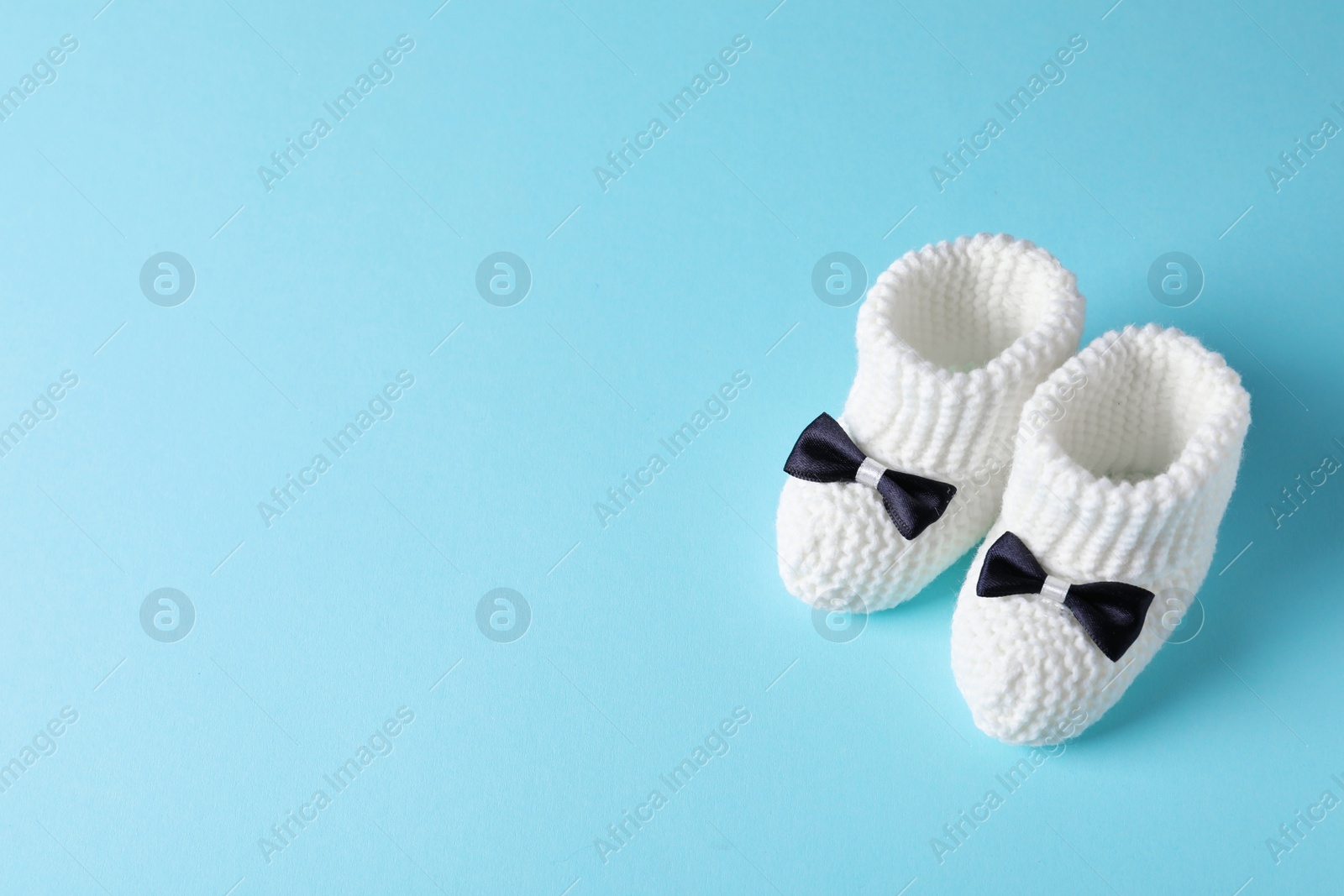 Photo of Handmade baby booties on color background. Space for text