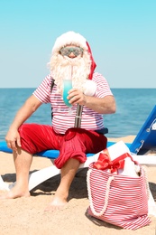 Photo of Authentic Santa Claus with cocktail resting on lounge chair at resort