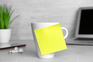 Photo of Cup with blank sticky note on white office table. Space for text