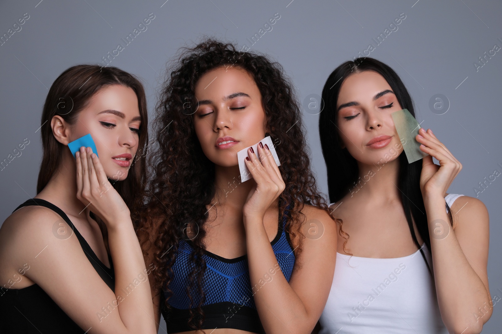 Photo of Beautiful women using mattifying wipes on grey background