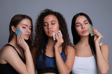 Photo of Beautiful women using mattifying wipes on grey background