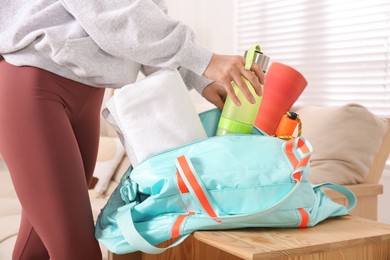 Woman packing sports stuff for training into bag at home, closeup