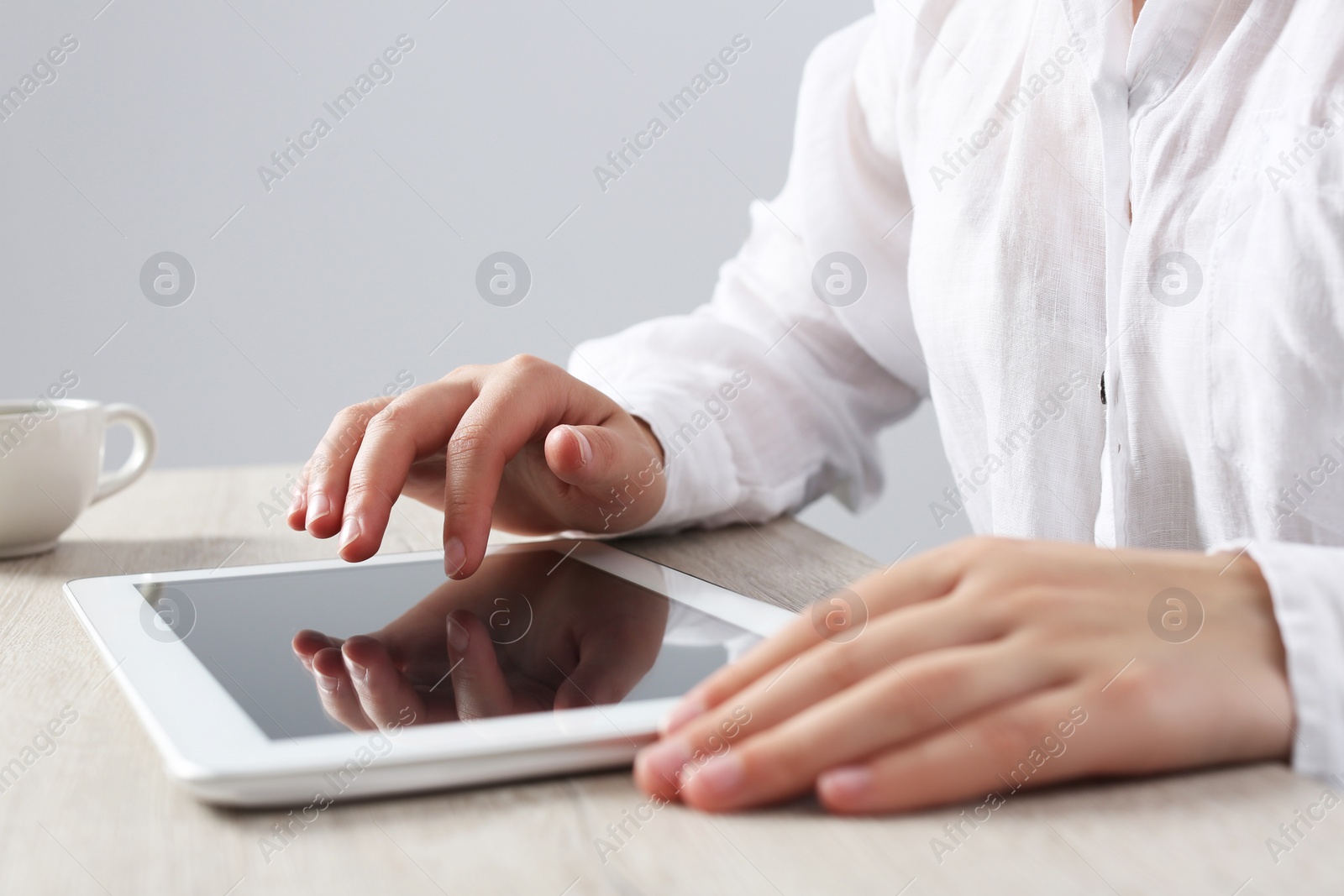 Photo of Woman using tablet at wooden table in office, closeup