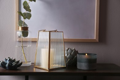 Photo of Burning candles and decor on wooden table indoors