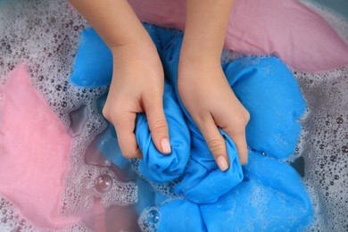 Woman washing blue garment in suds, closeup