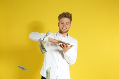 Young man throwing money on color background