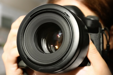 Female photographer with professional camera on blurred background, closeup