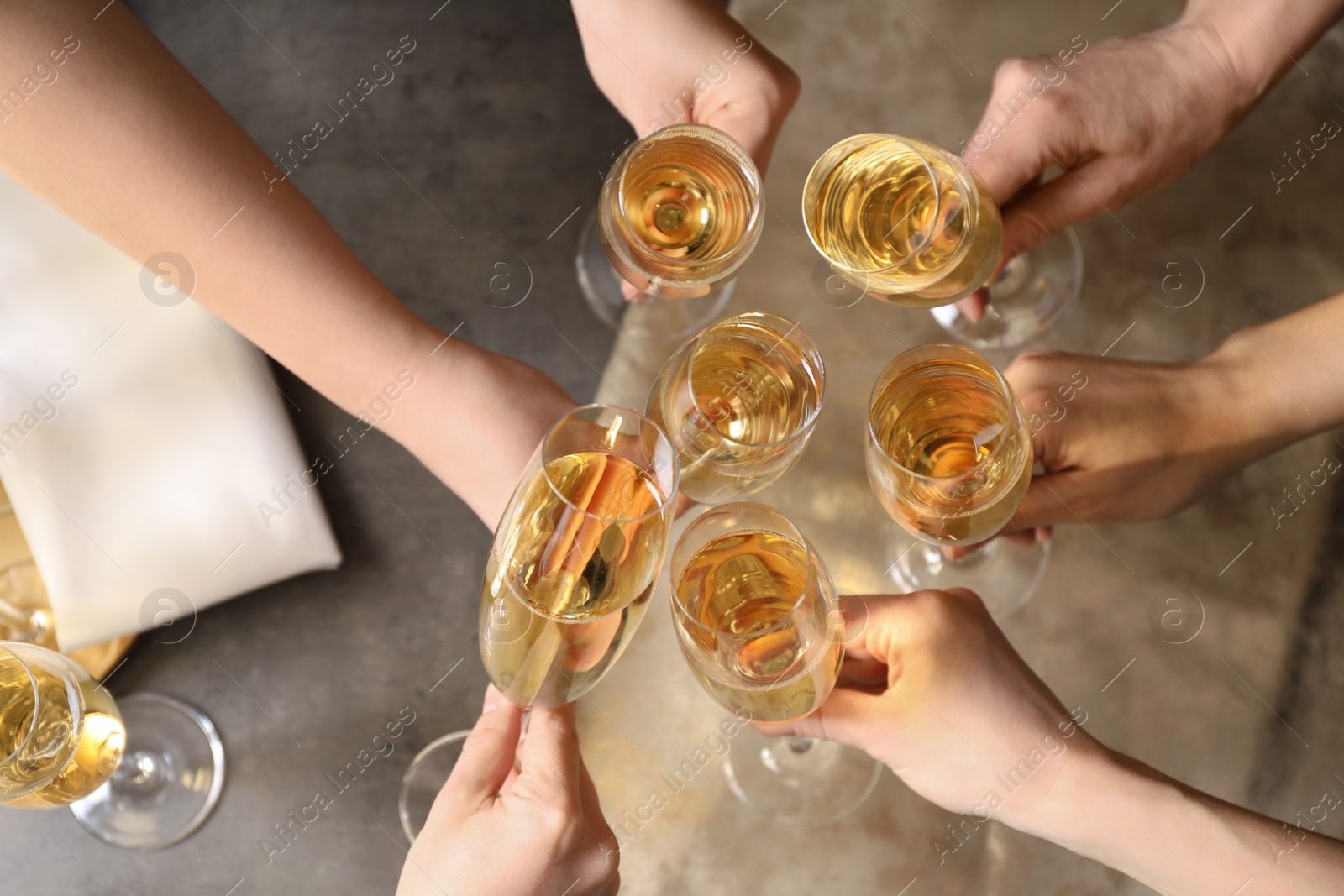 Photo of People clinking glasses with champagne over table, top view