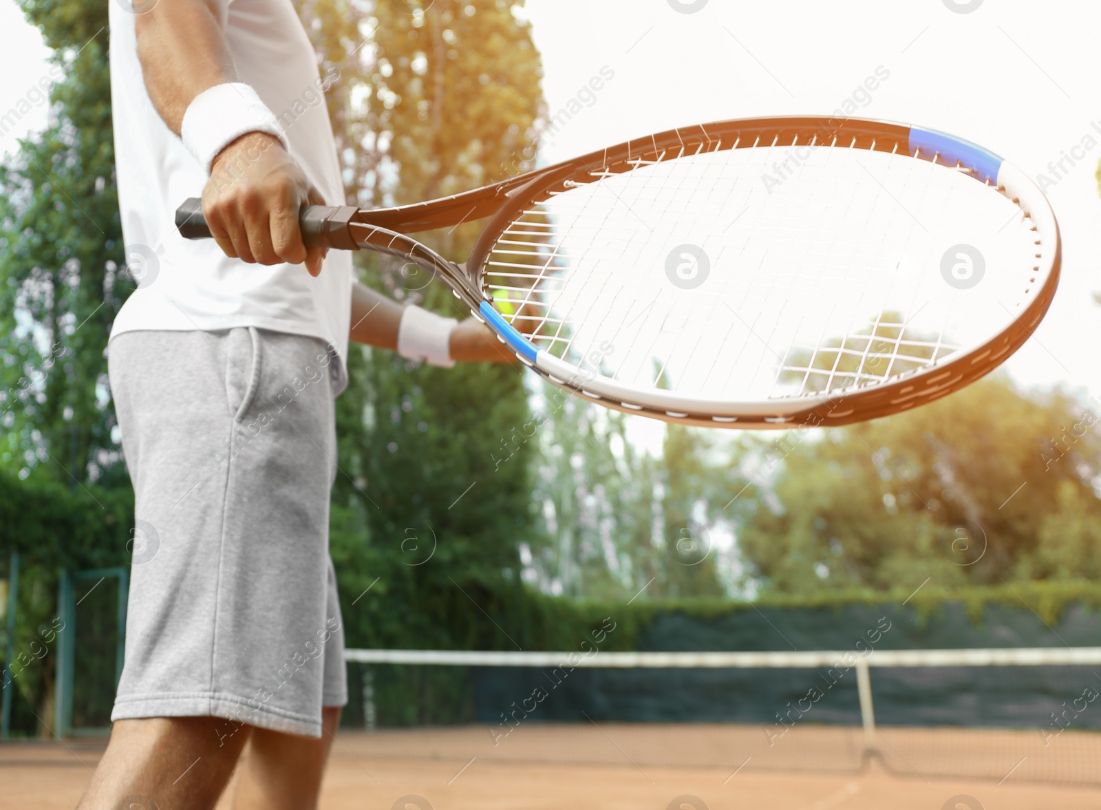 Photo of Sportsman playing tennis at court on sunny day, closeup