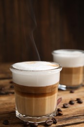 Photo of Delicious latte macchiato and coffee beans on wooden table