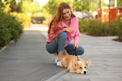 Young woman with her adorable Pembroke Welsh Corgi dog in park