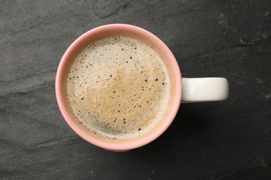 Photo of Cup of aromatic coffee on black table, top view