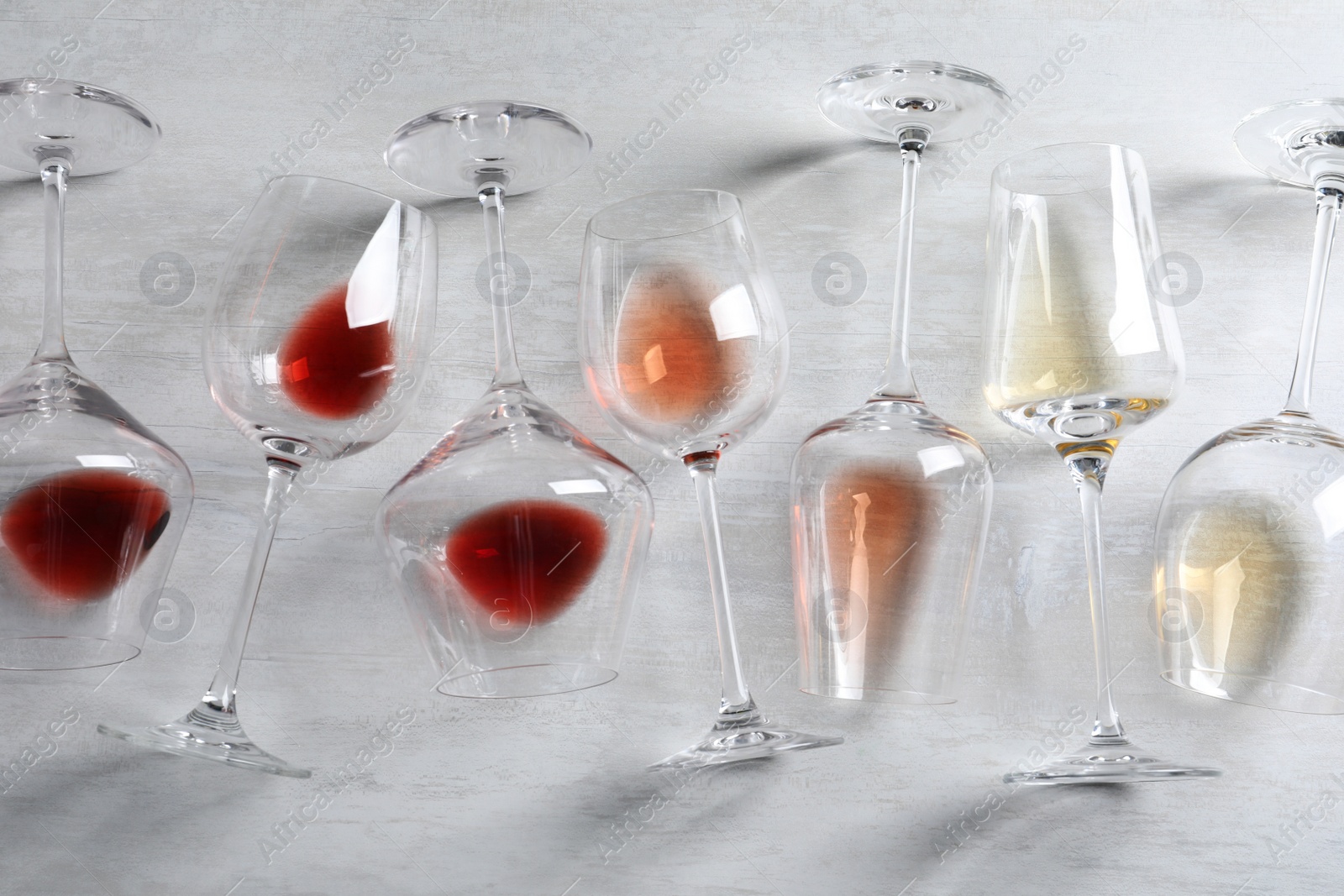 Photo of Different glasses with wine on light background, flat lay