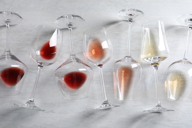 Different glasses with wine on light background, flat lay