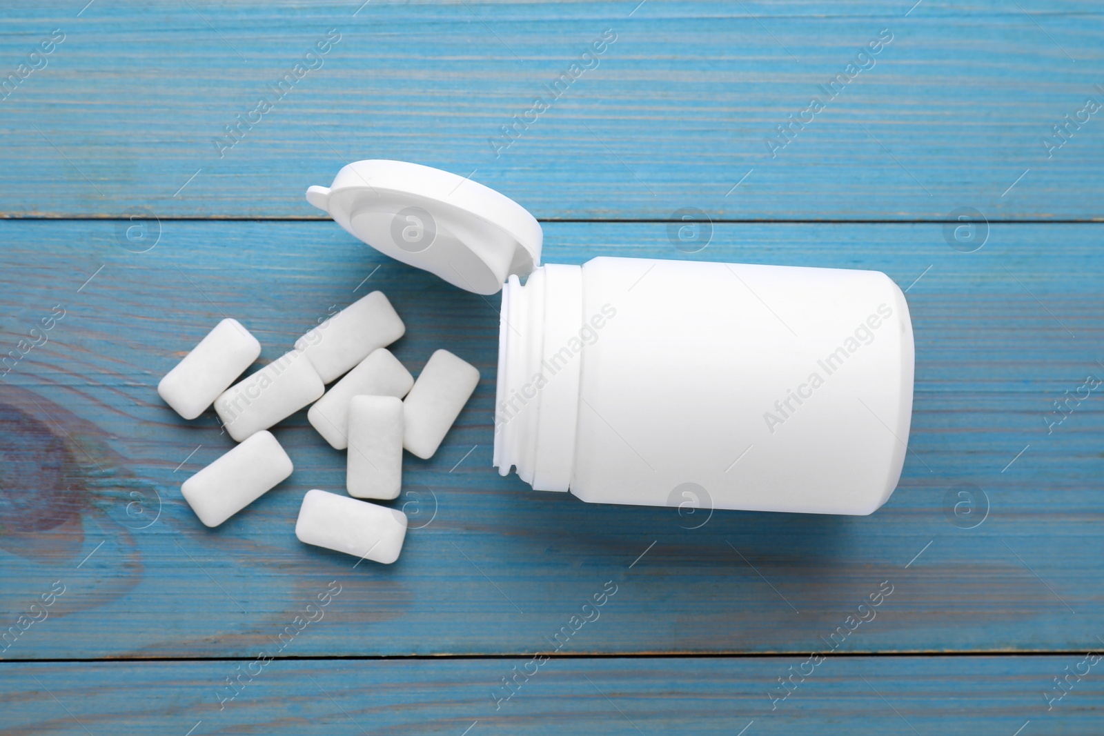 Photo of Jar with chewing gums on light blue wooden table, flat lay