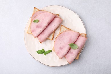 Photo of Delicious sandwiches with ham on light gray table, top view