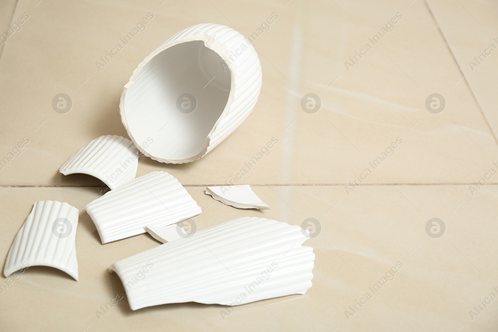 Photo of Broken white ceramic vase on floor. Space for text