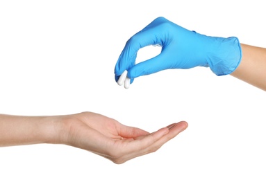 Doctor in medical glove giving pills to patient on white background