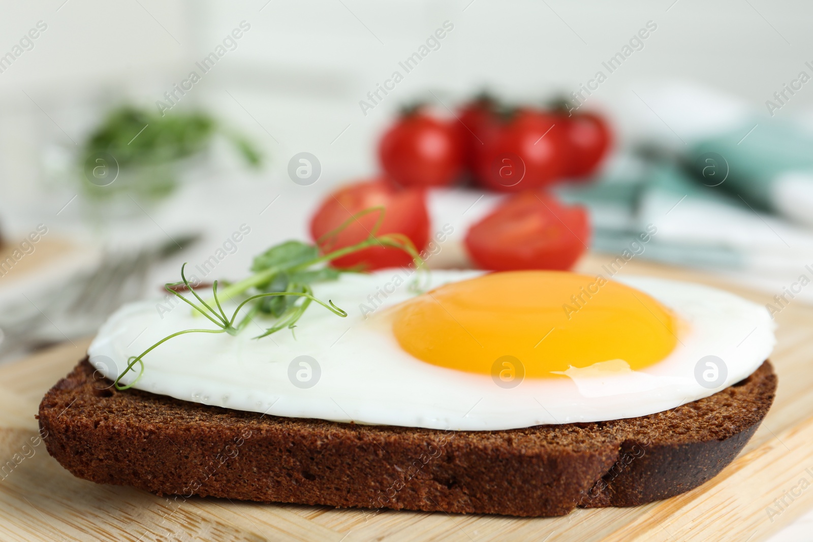 Photo of Tasty fried chicken egg with sprouts and rye bread on wooden board, closeup