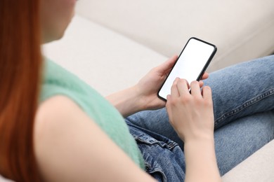 Woman using mobile phone indoors, closeup view