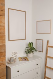 Photo of Blank frame hanging on light wall indoors. Space for design