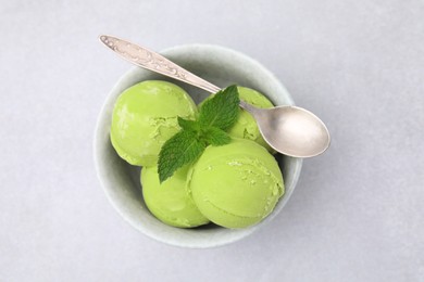 Photo of Tasty matcha ice cream and spoon in bowl on light grey table, top view