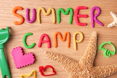 Photo of Text SUMMER CAMP made with play dough on wooden background, top view