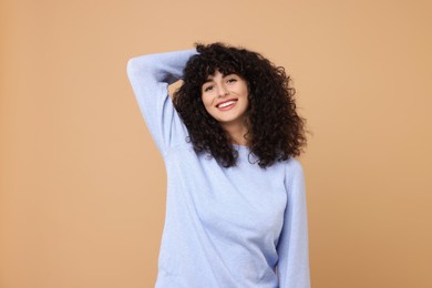 Happy young woman in stylish light blue sweater on beige background