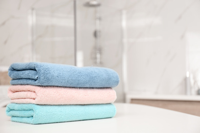 Photo of Stack of color towels on white table in bathroom, closeup. Space for text
