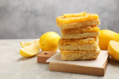 Photo of Stacked tasty lemon bars on light grey table, closeup. Space for text