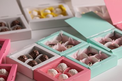 Photo of Boxes with delicious candies on white table, closeup. Production line