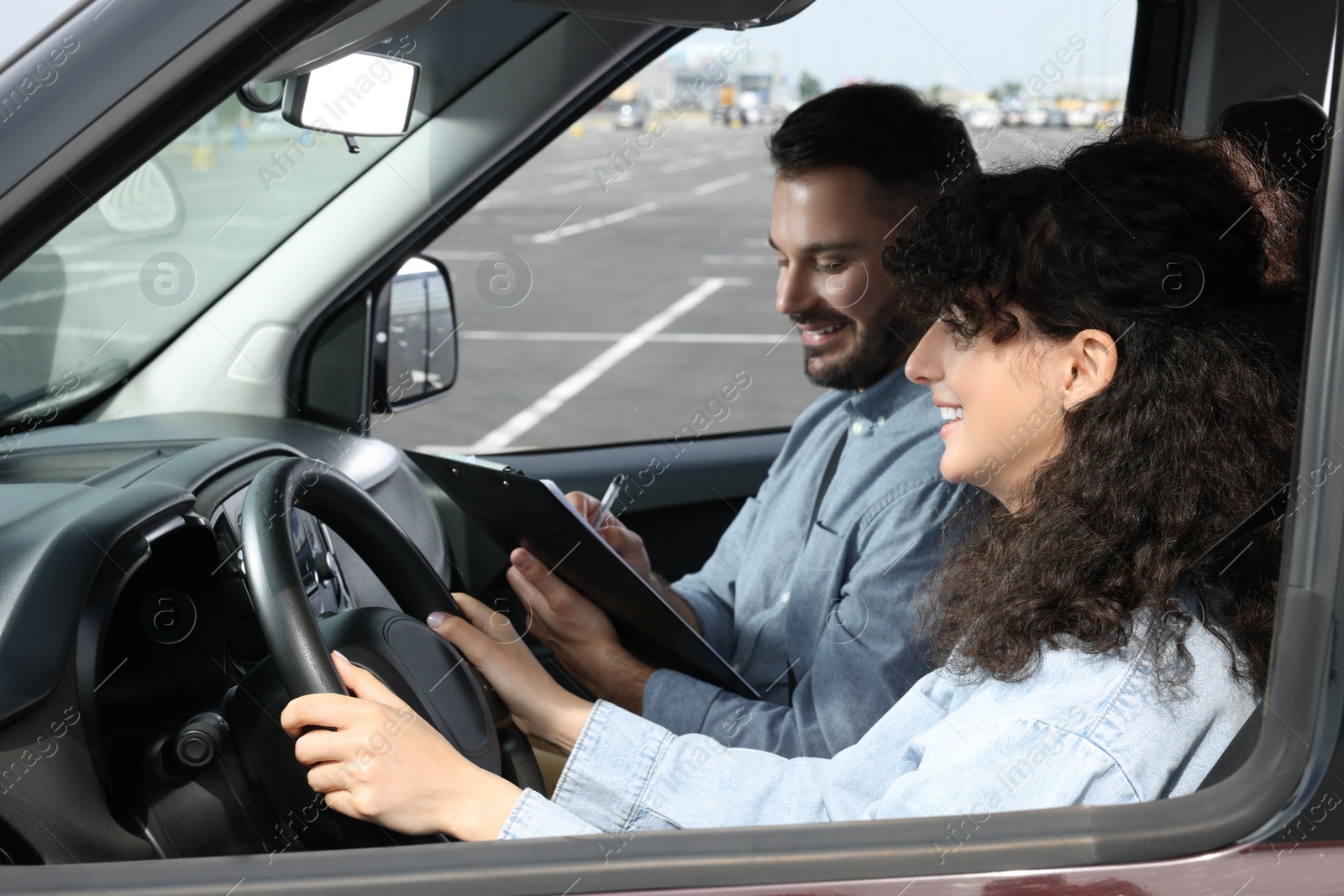 Photo of Driving school. Happy student passing driving test with examiner in car at parking lot