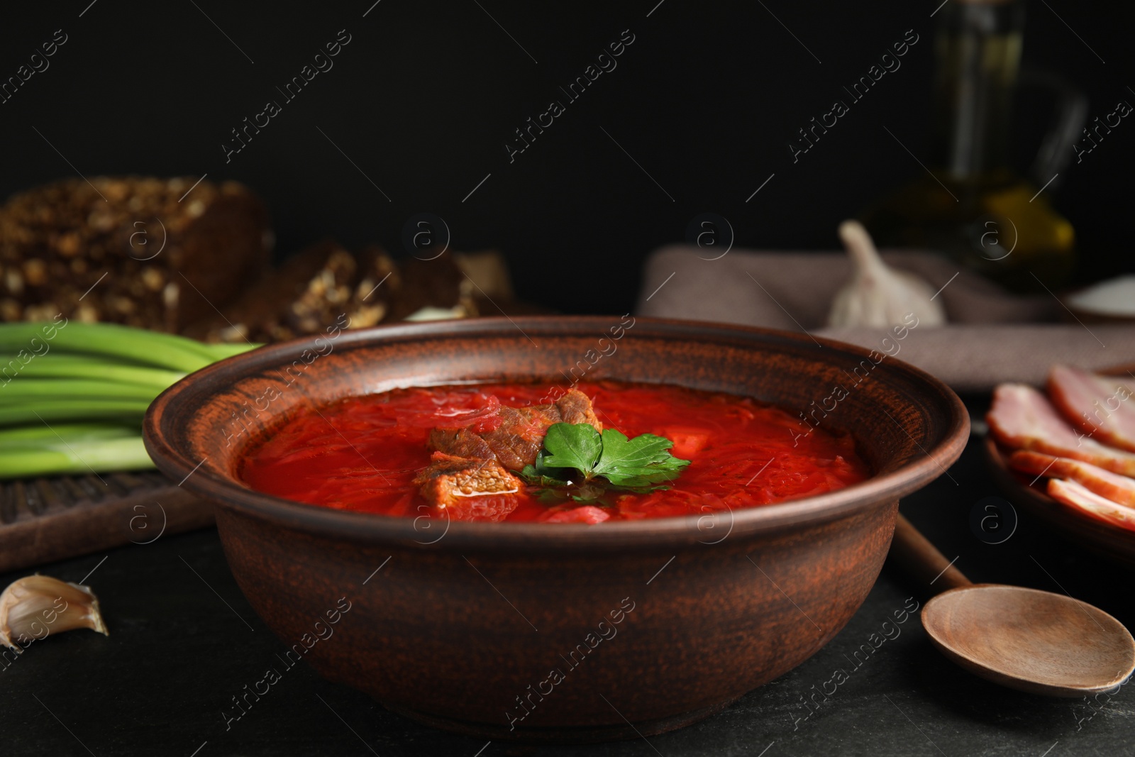 Photo of Stylish brown clay bowl with Ukrainian borsch served on black table