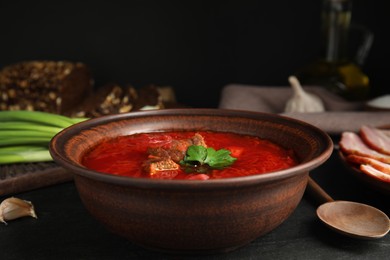 Stylish brown clay bowl with Ukrainian borsch served on black table