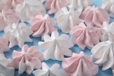 Tasty meringue cookies on light blue background, closeup