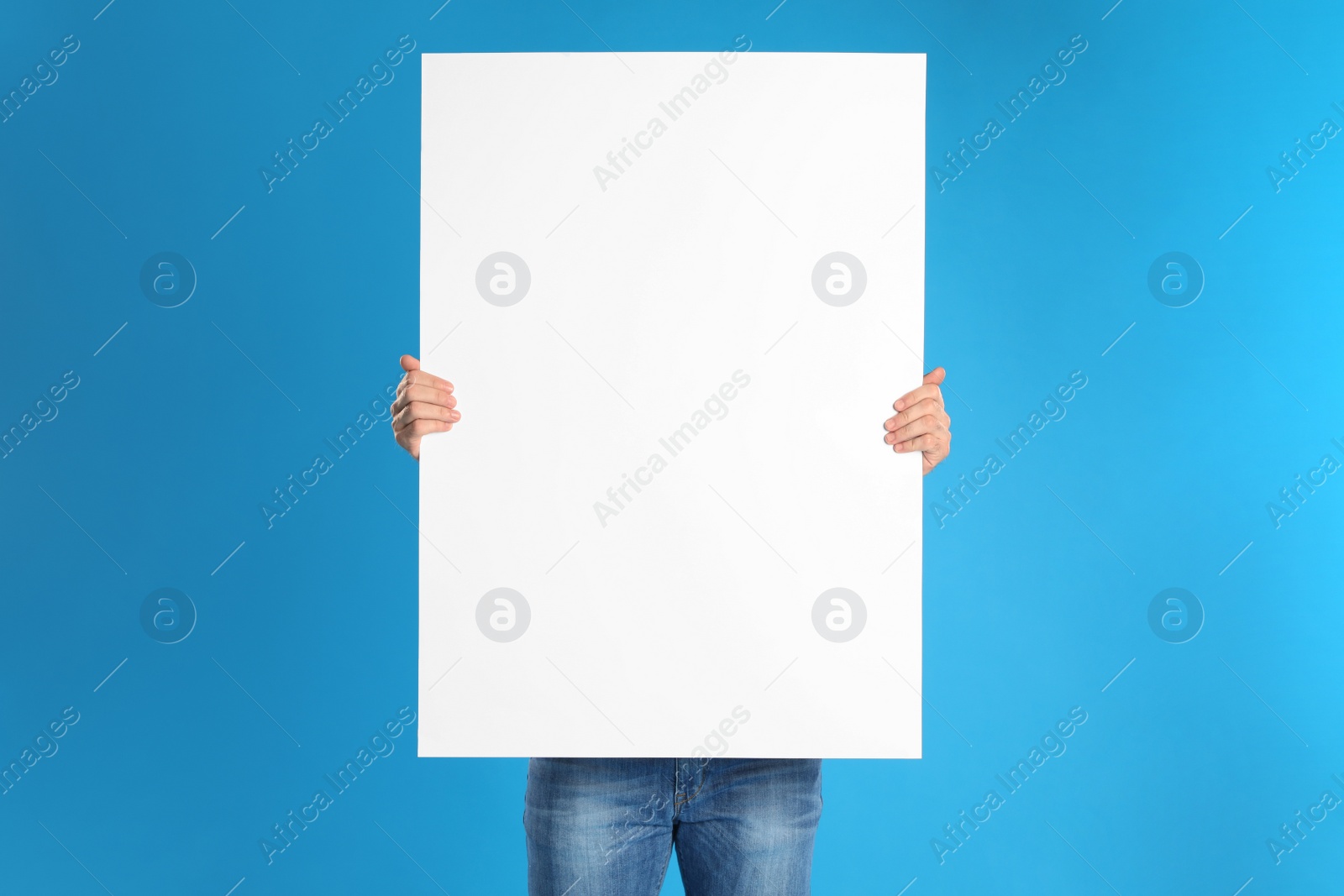 Photo of Man holding blank poster on blue background