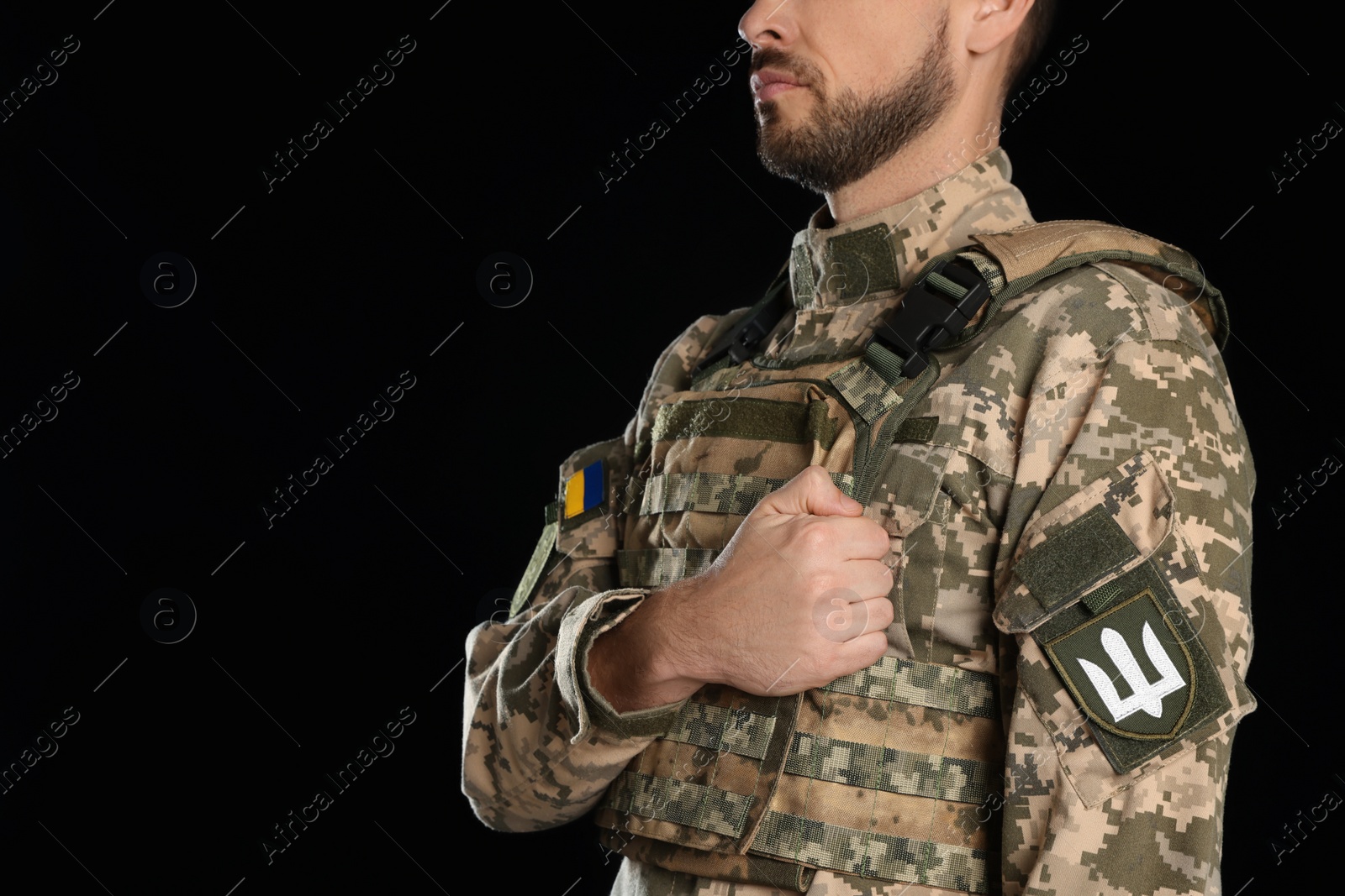 Photo of Soldier with Ukrainian trident on military uniform against black background, closeup. Space for text