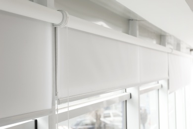 Photo of Modern window with white roller blinds indoors