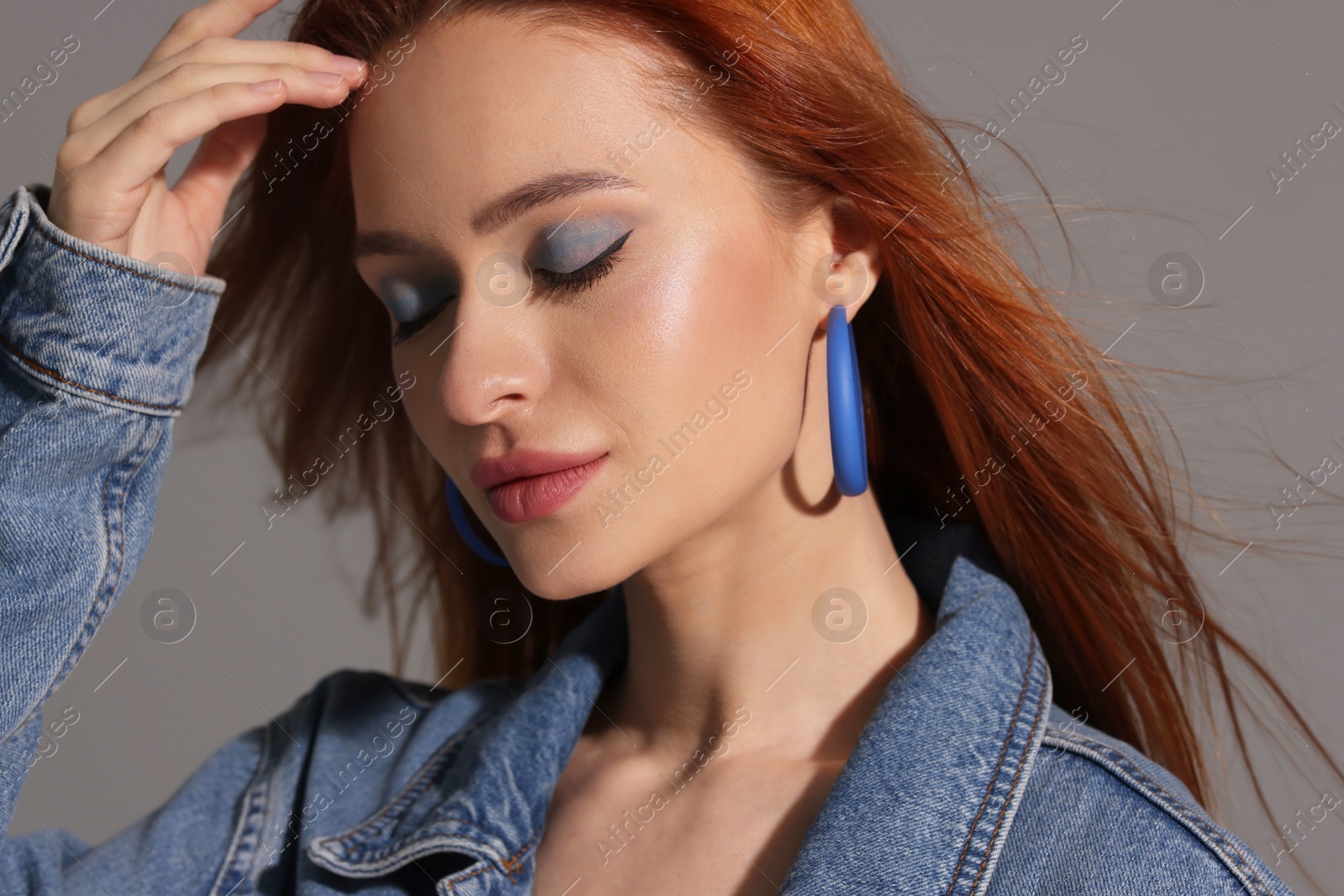 Photo of Beautiful young woman in denim jacket on gray background