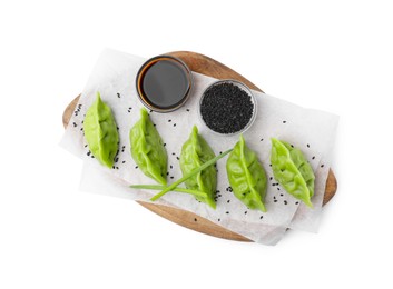 Photo of Delicious green dumplings (gyozas), soy sauce and sesame seeds isolated on white, top view