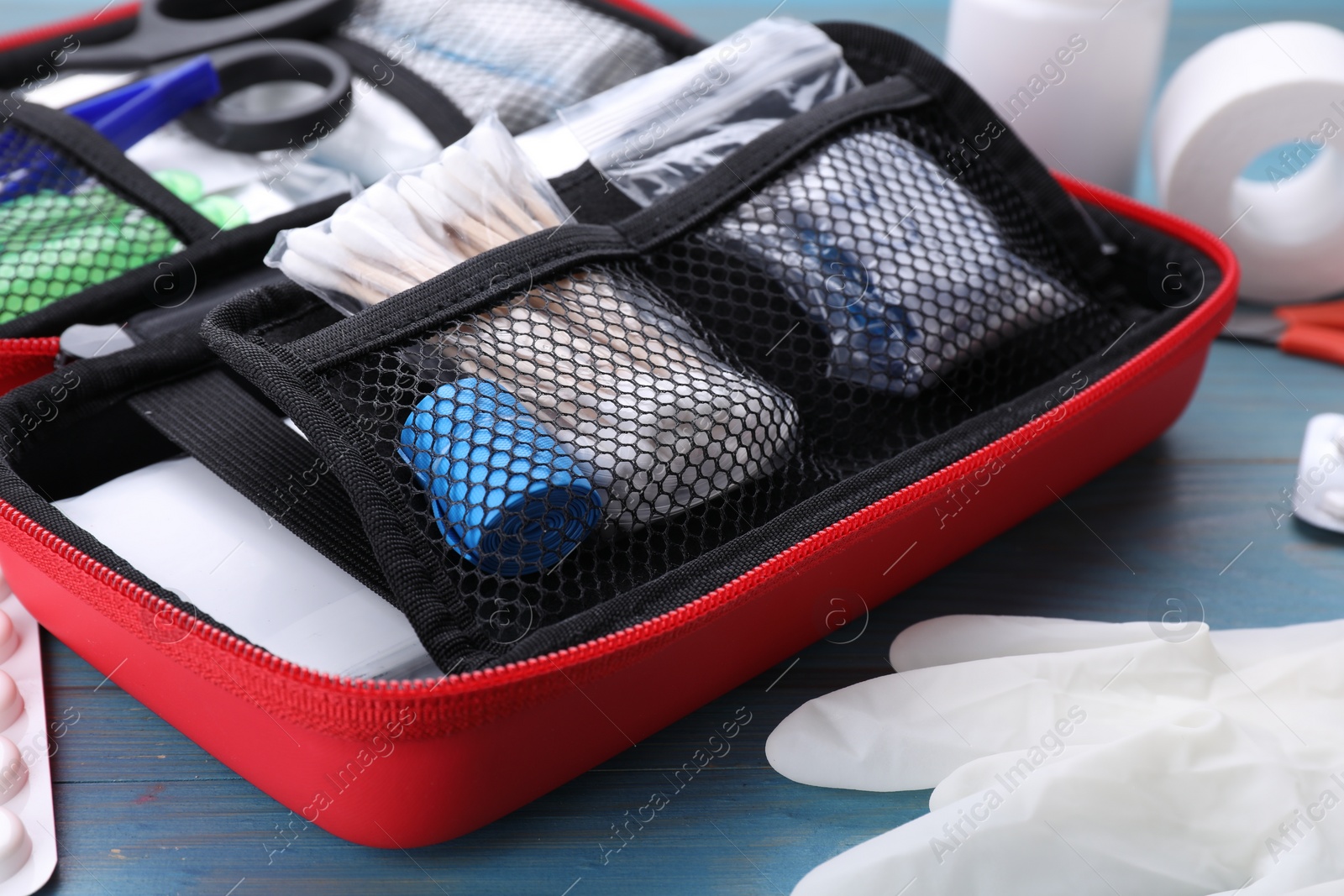 Photo of First aid kit on blue wooden table, closeup