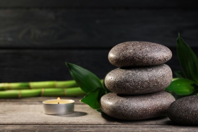 Photo of Spa stones, bamboo and candle on wooden table. Space for text
