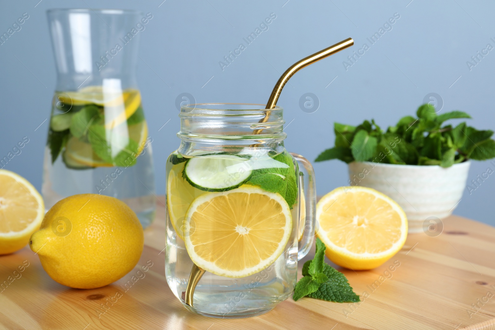 Photo of Refreshing water with cucumber, lemon and mint on wooden table