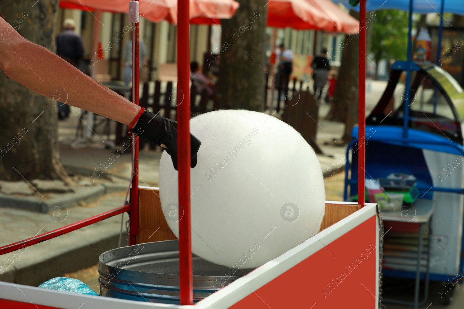 Photo of Man making cotton candy with machine outdoors, closeup