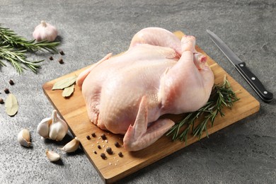 Photo of Fresh raw chicken with spices and knife on grey textured table